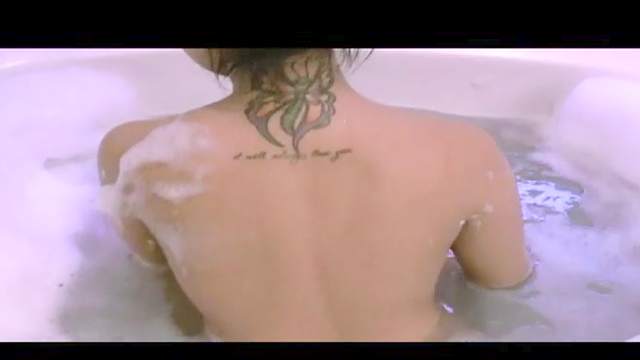 Dark-haired babe with nice tattoo is taking bath