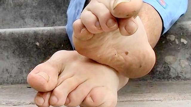 Dark-haired gay rubs his feet outdoors