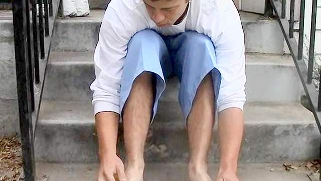 Dark-haired gay rubs his feet outdoors