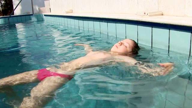 Smiling babe is getting topless in the pool