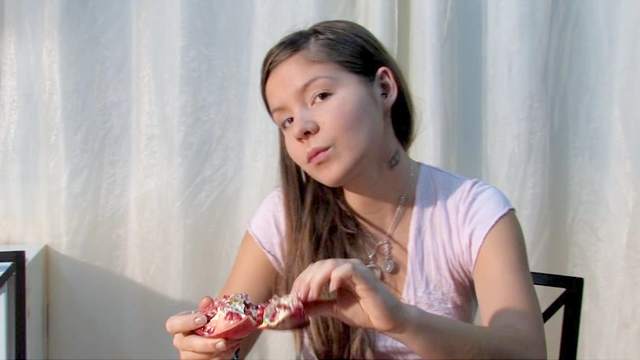 Topless teen is posing on a table in the kitchen