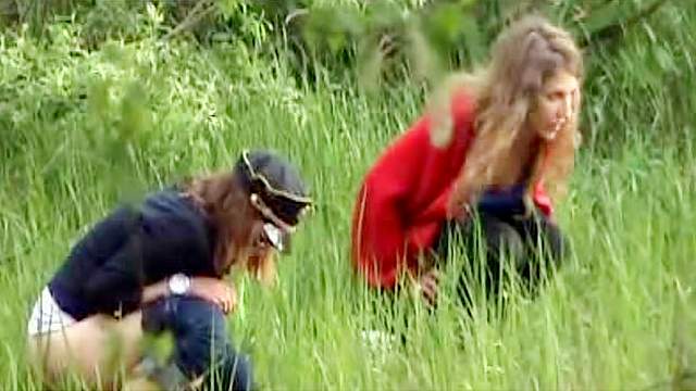 Two girls go pee in a field