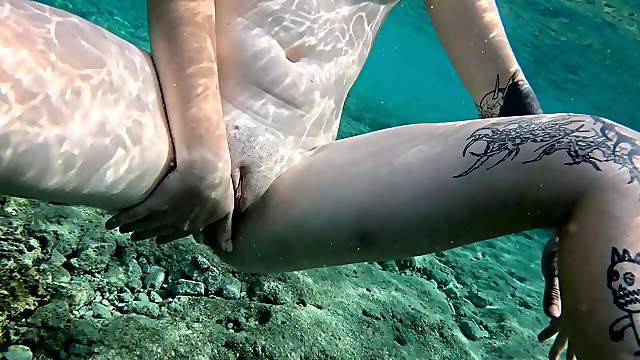 Tattooed brunette in glasses pleasures herself submerged