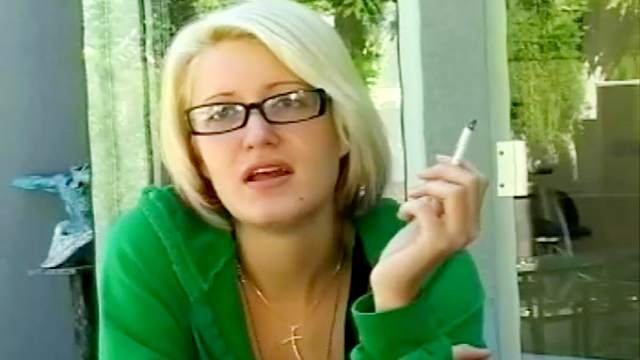 Sexy blonde is smoking a cigarette outdoors